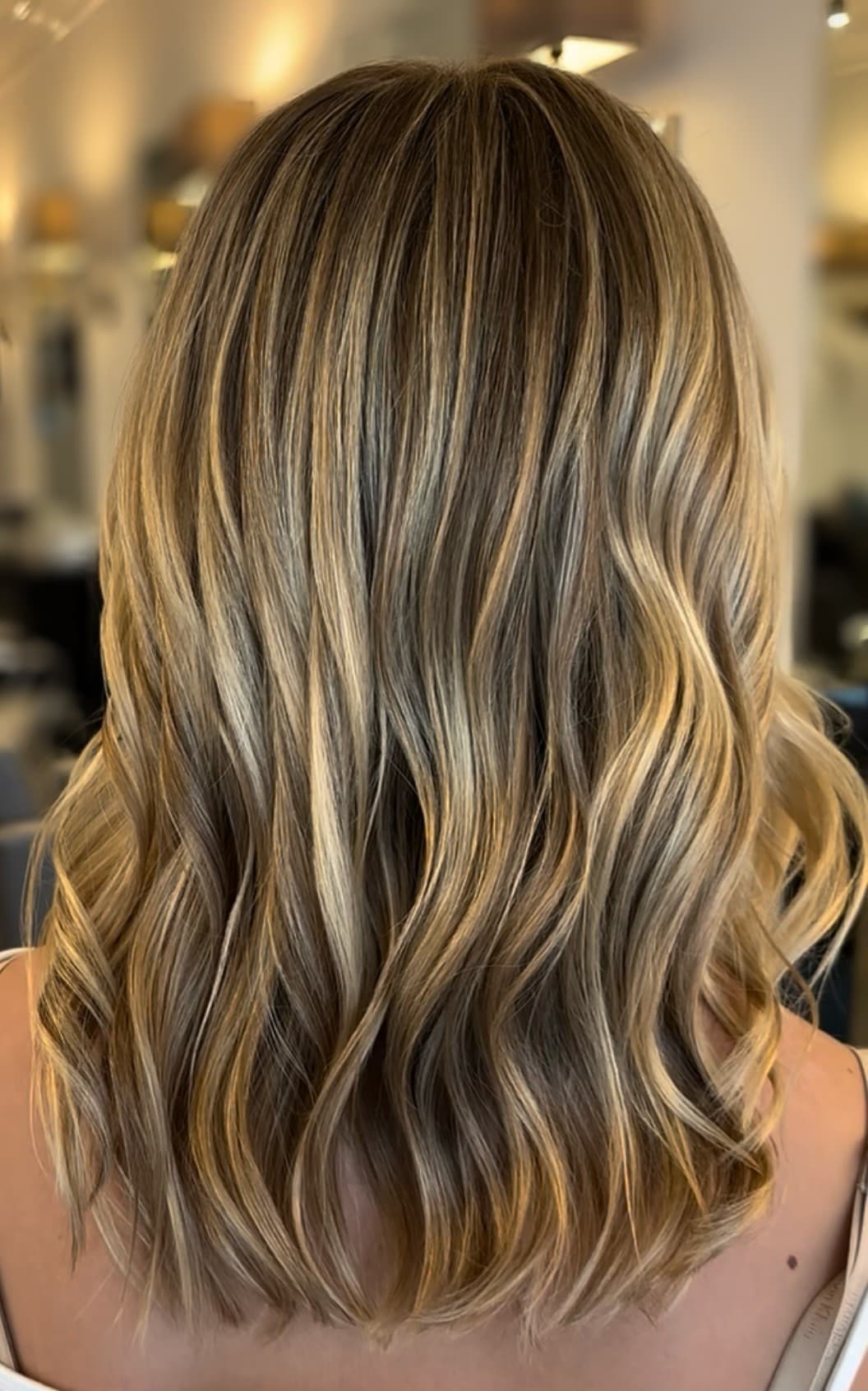 Warm blonde balayage result, styled in loose waves.