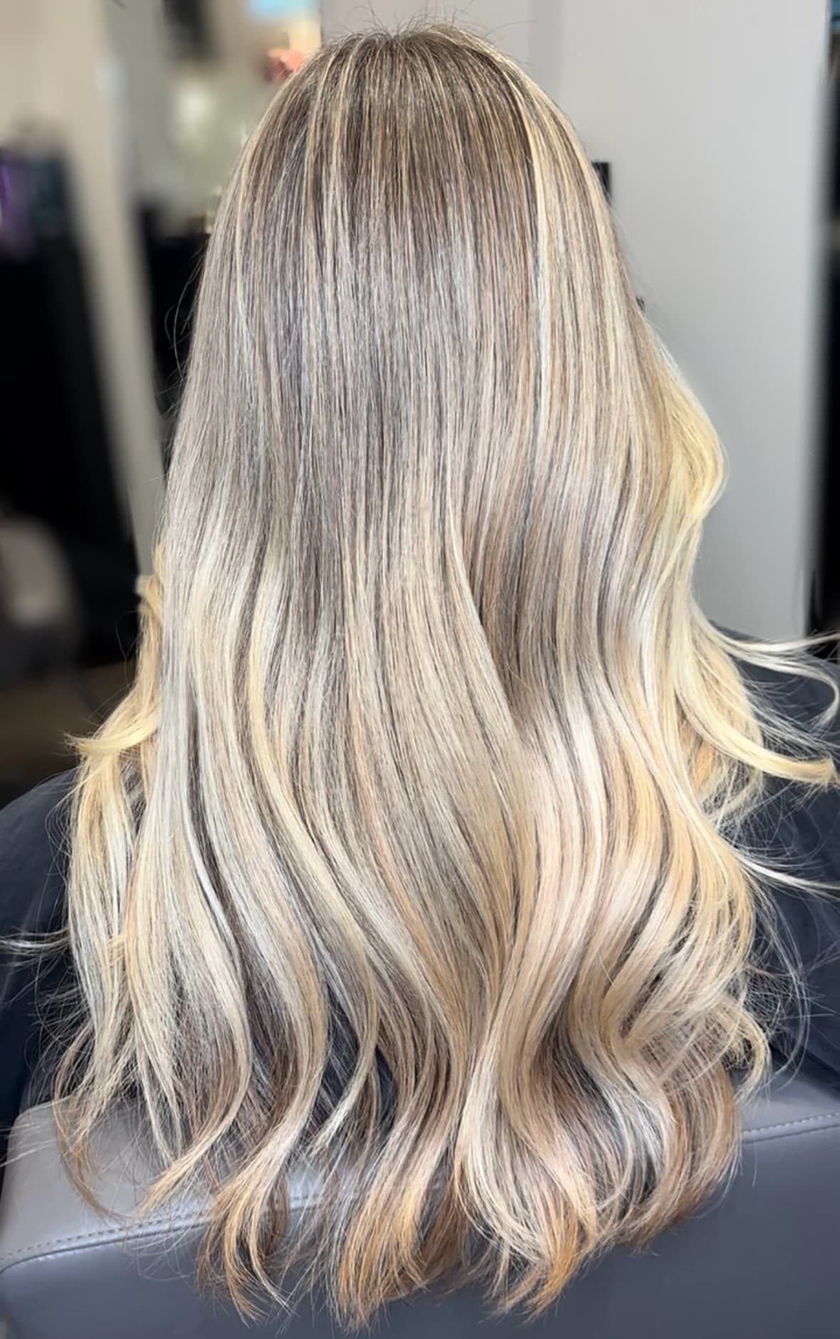 Warm dimensional blonde color result, styled in waves.
